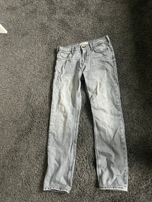 Ljusgrå raka jeans - Säljer ett par ljusgrå jeans med rak passform och klassisk femficksdesign. Jeansen har normal midja och är tillverkade i denim. Perfekta för en avslappnad och trendig look. Nypris 900 kr