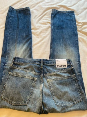 Blå jeans från Weekday - Säljer ett par helt nya jeans från weekday i en väldigt fin blå färg. dom är i 27/32 och är i en rak modell. säljer dom pågrund av att dom inte har kommit till användning.