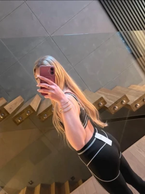 Svart sport-bh och tights från ALO - Säljer ett svart sportset från Alo med vita kontrastsömmar. Setet består av en sport-bh med bred resår och matchande höga tights. Materialet är stretchigt och passar perfekt för träning eller gym. Snygg och sportig look med diskret logga på linningen.