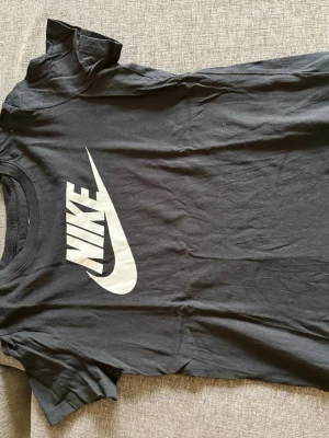 Svart Nike t-shirt med stor logga - Snygg svart t-shirt från Nike med stor vit logga och swoosh på bröstet. Klassisk passform och rund halsringning. Tillverkad i mjuk bomull som är skön att bära hela dagen.