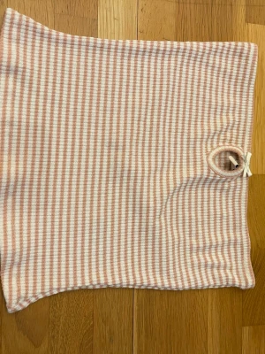 Randig tublinne i rosa och vitt - Säljer en mjuk och stretchig tublinne med smala ränder i ljusrosa och vitt från Nelly. Linnet har en enkel, rektangulär form och är tillverkad i ett ribbstickat material. Perfekt till sommaren.