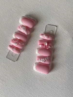 Press-on naglar rosa med 3D dekoration - Snygga press-on naglar i ljusrosa med vit fransk tipp och 3D dekorationer som pärlor och blommor. 