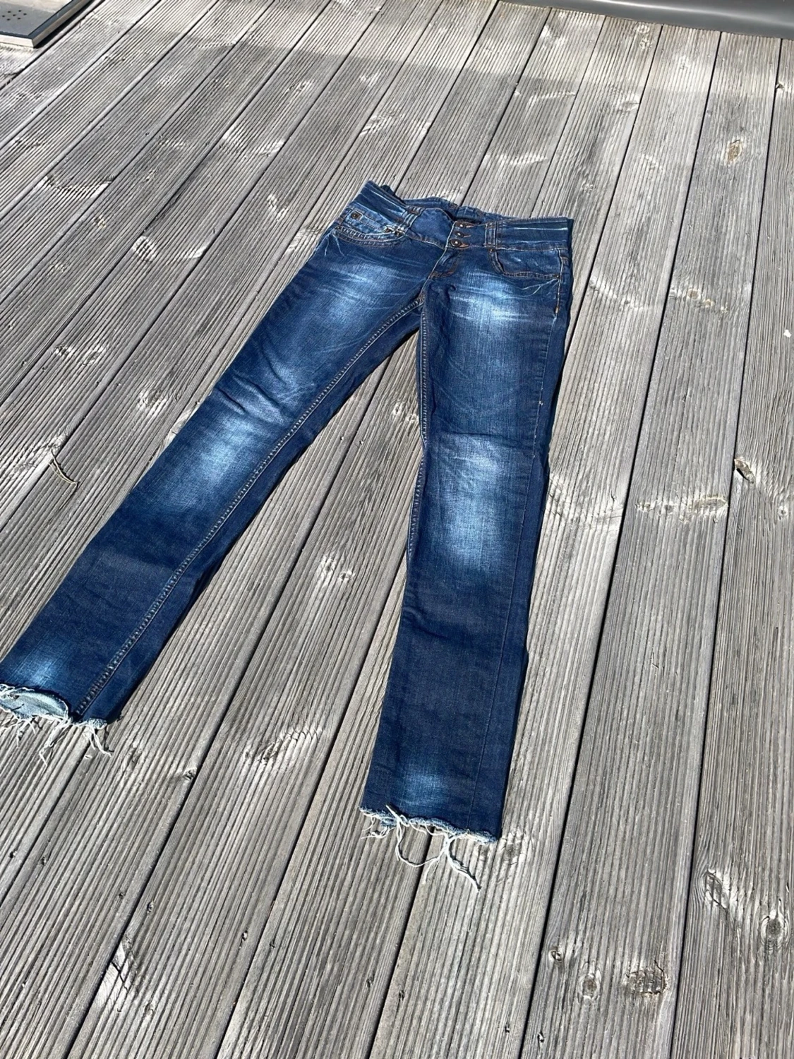 Mörkblå slitna jeans med rå kant