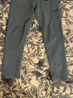 Blå hoodrich byxor S - Säljer ett par blå leggings med smal passform och en praktisk ficka på ena benet. Perfekta för en avslappnad stil och lätta att matcha med olika toppar. Materialet känns mjukt och stretchigt för extra komfort.