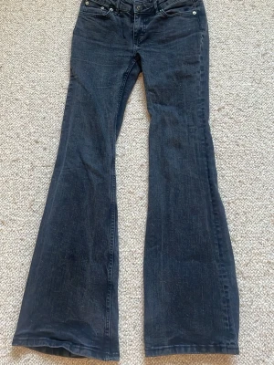 Mörkblå bootcut jeans - Snygga mörkblå bootcut jeans med klassisk femficksmodell och låg midja. Jeansen har utsvängda ben och är tillverkade i ett mjukt denimtyg som ger en avslappnad look. Perfekta för dig som gillar retrovibbar och vill ha ett par jeans som sticker ut.