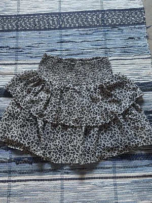 Leopardmönstrad volangkjol - Kort kjol med leopardmönster och dubbla volanger. Kjolen har en bred, smockad midja som ger en bekväm och flexibel passform. Perfekt för dig som vill sticka ut med ett djuriskt print. 💕 från kapphl 