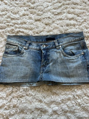 Blå jeanskjol - Säljer en super fin jeanskjol med fem fickor och coola små nitar på ena sidan. Shortsen har normal passform och rå kant nedtill för en avslappnad vibe. Perfekta till sommaren och lätta att matcha med allt. Pris kan diskuteras 