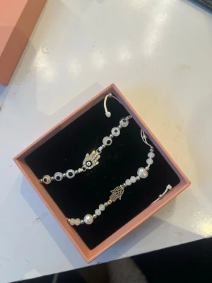 Två vita pärlarmband  - Säljer två armband med vita pärlor och silverfärgade detaljer. Båda armbanden har justerbar knytning och passar perfekt för dig som gillar fina utomlands armband. (Finns även på Vinted, samma användarnamn)💞💞