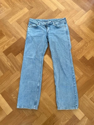 Ljusblå lågmidjade jeans i modell arrow - Säljer ett par ljusblå jeans med rak passform och klassisk femficksdesign. Jeansen har en låg midja och är tillverkade i denim med en snygg tvätt. Perfekta för en avslappnad och trendig look.