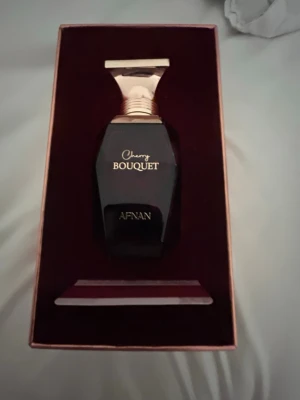 Cherry Bouquet parfym från Afnan - Cherry Bouquet från Afnan är en lyxig parfym i en mörkröd, elegant flaska med gulddetaljer. Förpackningen är stilren och har körsbärsmotiv på framsidan. Doften är inspirerad av körsbär och passar dig som gillar fruktiga och söta parfymer.Använd några gånger.