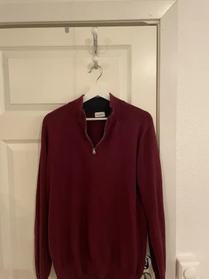 Vinröd halvzip tröja John Henric - Snygg vinröd tröja från John Henric med halv dragkedja och ståkrage. Tröjan har långa ärmar och ribbade muddar. Perfekt för lager på lager och stilrena outfits. Materialet känns mjukt och bekvämt.