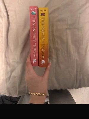 This Woven Kingdom & These Infinite Threads - Två böcker av Tahereh Mafi: 'This Woven Kingdom' med gul-orange omslag och rosor, samt 'These Infinite Threads' med rosa omslag. Båda är pocketböcker på engelska och tillhör fantasygenren. Perfekt för dig som gillar magi, romantik och episka äventyr. På engelska säljer båda, har inte använt 