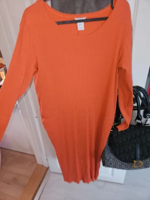 Ribbad orange långklänning Lindex - Säljer en ribbad långklänning från Lindex i en snygg orange färg. Klänningen har lång ärm och rund halsringning, perfekt för dig som gillar enkel men trendig stil. Materialet är mjukt och stretchigt för en bekväm passform.