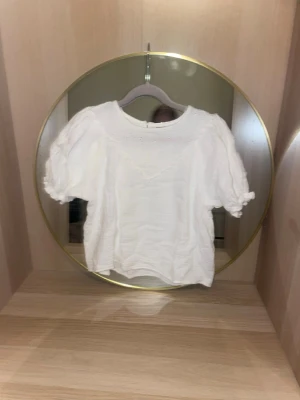 Vit puffärmad blus i storlek 146(xs) - Söt vit blus med puffiga korta ärmar och rund halsringning i storlek 146(sitter som xs/s) Blusen har en lätt strukturerad bomullskänsla och knappdetalj i nacken. Perfekt till jeans eller kjol för en fräsch look.skriv för fler bilder, pris kan diskuteras!💗