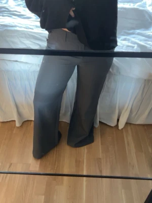 Gråa raka kostymbyxor - Säljer ett par gråa kostymbyxor med mid waste midja och raka ben. Byxorna har klassisk passform med hällor för skärp och diskreta fickor. Helt oanvända.