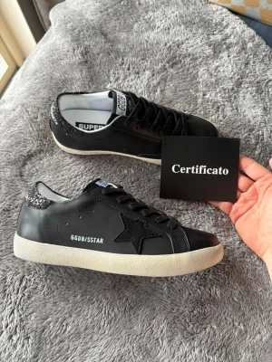 Golden Goose Superstar  Svart med Glitter - Säljer nu mina fina Golden Goose Superstar med svart glitter! De är helt ny skick, aldrig använda! Köpte de på en outlet i Italien men när jag kom hem så insåg jag att de inte var för mig. Box, certifiering och skorna medföljer! Nypris är ca 6000kr🤗PS! Jag accepterar bud…