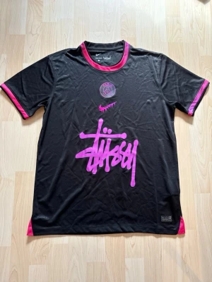 PSG x Stüssy ”Paris Noir” Kit 2025/26 - Stilren fotbollströja i helt nytt skick. Tröjan är inte använd en endaste sekund. PSG tröjan kombineras med det exklusiva streetwear märket Stüssy.