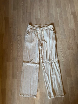 Beiga linnebyxor från Grunt - Snygga beiga linnebyxor från Grunt i storlek XL (barnstolek). Byxorna har raka ben, dragsko i midjan och sidofickor. Tillverkade i ett luftigt linnematerial som passar perfekt för varma dagar. Enkel och avslappnad stil som är lätt att matcha. Nypris 400kr mitt pris 120kr.