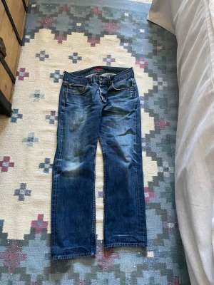 Selvedge jeans - Säljer ett par klassiska blå jeans med raka ben och snygga slitningar framtill. Jeansen har fem fickor och normal midja. Perfekta för en avslappnad och trendig look. Materialet är denim i bomull. SELVEDGE DENIM MADE IN JAPAN