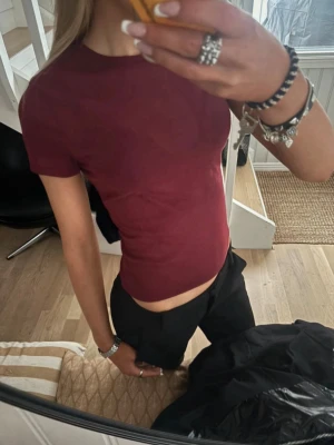 Mörkröd tight t-shirt - En enkel och stilren mörkröd t-shirt med tight passform och korta ärmar. Perfekt att matcha med både jeans och kjol för en clean look. Materialet känns mjukt och följsamt mot kroppen.