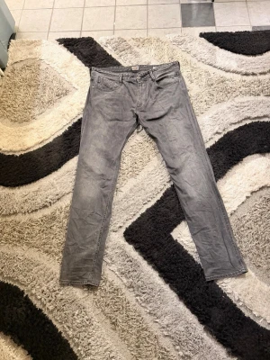 Grå jeans från Replay - Snygga grå jeans från Replay med klassisk femficksmodell och raka ben. Jeansen har en diskret tvättad look och är tillverkade i ett mjukt denimtyg som ger en skön känsla. Perfekta för dig som vill ha en stilren och avslappnad vibe.