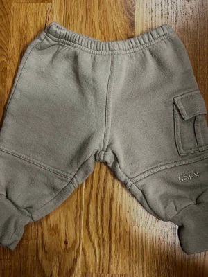 Gröna barn / baby byxor från Lindex - Storlek 62 - Ett par babybyxor från Lindex i fin grön färg! Perfekta för både lek och vila! Byxorna har resårmudd i midjan och vid bensluten för en bekväm passform, samt en söt liten ficka på ena benet. På byxorna finns även ett diskret tryck med texten “little baby”. Storlek: 62 (2–4 månader) Material: 80% Bomull och 20% Polyester. Säljs i mycket bra skick! Kika gärna in på mina andra annonser, jag säljer flera barnplagg just nu! Hör av dig vid frågor!