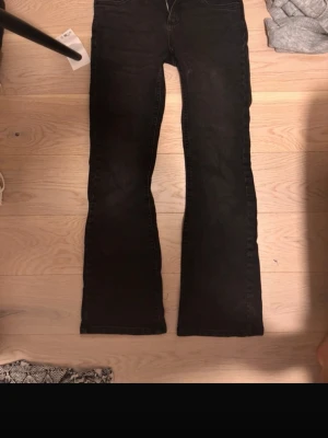 Svarta bootcut jeans i denim - Säljer ett par svarta bootcut jeans i klassisk femficksmodell. Jeansen har en lätt utsvängd passform nedtill och är sydda i mjukt denimtyg. Perfekta för dig som gillar en tidlös och avslappnad look.