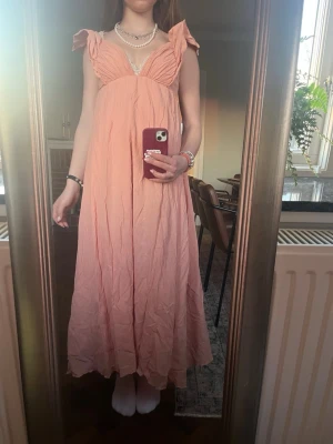 Orange långklänning HM - Säljer nu min så populära långklänning från HM. Endast använd några gånger så i nyskick utan defekter. Så fina detaljer! Perfekt korall orange när man är brun. Stretchiga i tyget så passar defenetivt större storlekar också. 