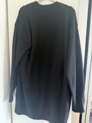 Lång kofta  - Storlek: S Skick: bra Beskrivning: En lång, finstickad kofta i mjuk kvalitet med inslag av ull. Koftan har nedhasad axel och lång ärm. Ribbstickad kant i nacken, vid ärmslut och nedtill. Saknar knäppning.