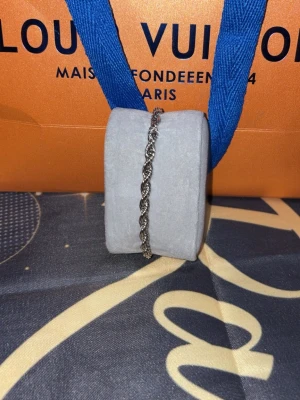 Silverfärgat tvinnat armband - Snyggt armband i silverfärg med tvinnad kedja som ger en cool och stilren look. Perfekt accessoar för att lyfta din outfit och passar till många olika stilar. Armbandet har en enkel men elegant design.