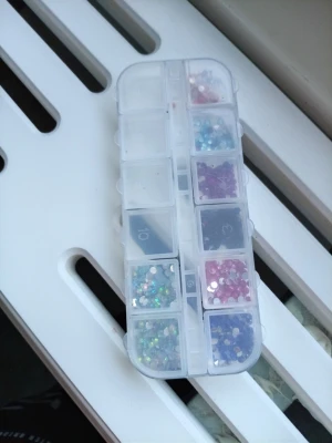 Nagelstenar i mixade färgerna  - Nagelstenar i olika färger som rosa, blå, lila. för dekoration av naglar. Kommer i en praktisk transparent plastask med flera fack för enkel förvaring och sortering. Perfekt för att skapa kreativa och glittriga nageldesigner.