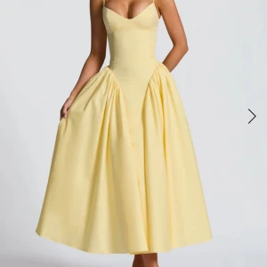 Ljusgul långklänning med snörning - Supersöt långklänning i ljusgul färg med smala axelband, markerad midja och vidd i kjolen. Klänningen har snygg snörning i ryggen och en feminin, v-ringad urringning framtill. Perfekt för sommarens alla tillfällen!