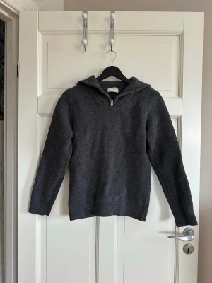 Mörkgrå stickad tröja med halvzip - Mörkgrå stickad tröja med halv dragkedja och hög krage. Tröjan har lång ärm och i 100% ull. Var egentligen min pappas men den krympte i tvätten. Passar storlek xs💕