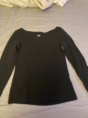 Svart långärmad topp  - En enkel svart långärmad topp från 157 med rund halsringning. Tillverkad i mjuk bomull som känns skön mot huden. Perfekt basplagg att matcha med olika stilar och accessoarer.