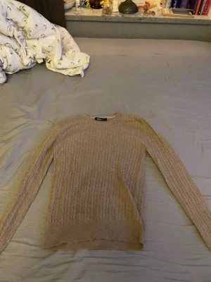 Beige ribbstickad tröja Gina Tricot - Säljer en beige ribbstickad tröja från Gina Tricot. Tröjan har rund halsringning, långa ärmar och är tunnstickad vilket gör den perfekt för lager på lager. Enkel och stilren design som passar till det mesta.