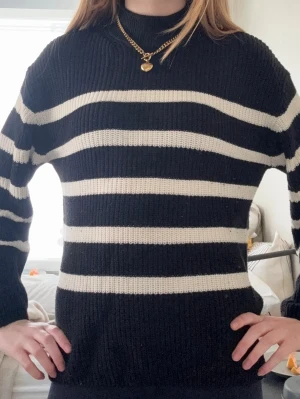 Svartvit randig stickad tröja KappAhl - Trendig stickad tröja från KappAhl i svart med breda vita horisontella ränder. Säljer pga att den är lite för kort i ärmarna på mig!
