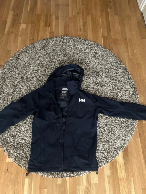 Svart/marinblå vindjacka från Helly Hansen - Stilren svart vindjacka från Helly Hansen, helt oandvänd , 10/10 skick! S men passar M