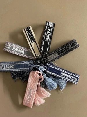 Broderade armband från Christian Dior - LÄS!!! säljer de begiea lr de mörkblåa lyxiga och stilrena tygarmbanden från Christian Dior. Armbanden har en vävd design med vita detaljer längs kanterna och känns både trendigt och exklusivt. Perfekt accessoar för att lyfta din outfit med en lyxig touch. Armbanden är köpt på dior i spanien, kvittot är borttappat därav kan priset diskuteras. Är öppen för alla förslag och ibland byten beroende på vad det är! Tveka inte på att höra av dig!
