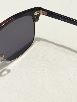 Ray-Ban Clubmaster solglasögon - Snygga Ray-Ban Clubmaster solglasögon med mörka linser och klassisk brunsköldpaddsmönstrad båge. Guldiga metalldetaljer och retroinspirerad form ger en tidlös look. Lådan har jag tyvärr tappat bort men går att fixa en ny fast av annat märke om det behövs.