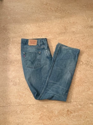 Levi's Strauss and co. - Klassiska blå jeans från Levi's med rak passform och fem fickor. Jeansen har en ljus tvätt och den ikoniska läderlappen bak i midjan. Tillverkade i slitstarkt denim med en avslappnad look och diskreta slitningar. Perfekta för en casual stil.