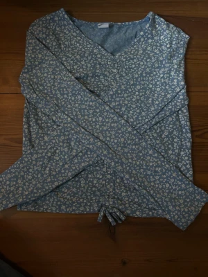 Småblommig tröja - Söt ljusblå tröja med vita blommor. Perfekt till sommaren o lätt att matcha med kjol eller jeans. Strl 170/xs. Använd endast 1/2ggr. Skriv om du har frågor!