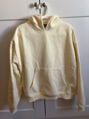 Krämvit hoodie från 157 - Säljer en krämvit hoodie från 157 i storlek M. Hoodien har en klassisk huva, stor magficka och ribbade muddar vid ärmar och nederkant. Tillverkad i mjukt material som känns skönt mot huden. Perfekt för en chill och avslappnad stil.