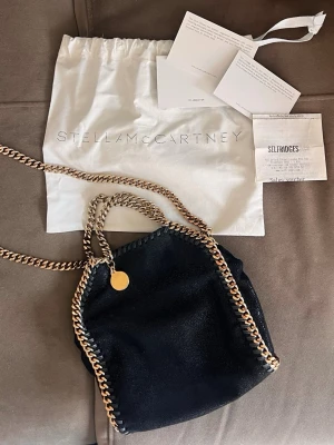 Stella McCartney tiny Falabella  - Stella McCartney väska! Svart med guldkedja. Så söt att bära i handen eller över axeln. 🥰