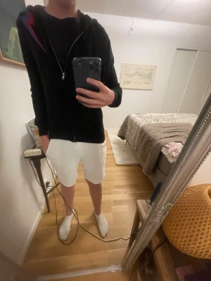 Svart hoodie med dragkedja från BVALDI - Svart hoodie från BVALDI med dragkedja framtill och huva med dragsko. På bröstet finns en snygg detalj i rött och blått. Tillverkad i mjukt material som känns skönt mot huden. Perfekt för en avslappnad och cool stil. ⭐️limited edition⭐️