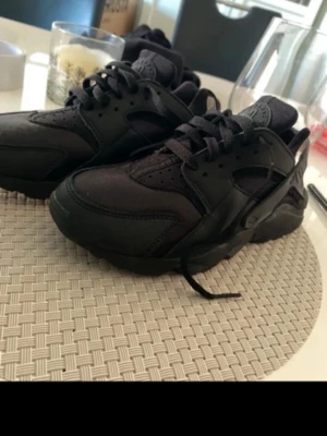 Helvita svarta sneakers - Säljer ett par helsvarta sneakers med chunky sula och klassisk snörning. Skorna har en mix av textil och syntetmaterial med coola detaljer och perforeringar på tån. Perfekta för dig som gillar en clean och sportig look.