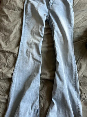 Ljusblå bootcut jeans - Säljer ett par ljusblå jeans med bootcut passform och klassisk femficksdesign. Jeansen har normalhög midja och dragkedja med knapp framtill. Perfekta för dig som gillar en avslappnad och trendig stil.
