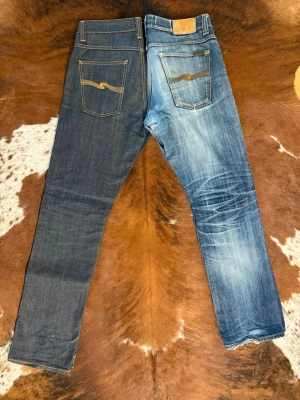 Nudie AvrageJoe DrySelvage - Tjena! Säljer dessa extremt sällsynta nudie jeans i modellen AvrageJoe: byxorna är helt nya förutom att jag använt dom 1 gång: Säljer dom då dom är alldeles för små för mig: Hör av dig vid funderingar: pris är ej diskutabelt  Only ONE pair of jeans is for sale – the DARK BLUE ones. The light blue jeans in the photos are my private pair, just to show how this denim could fade over time since that is the whole point with dry jeans. You are buying the dark blue jeans only