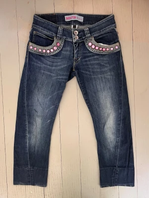 2000s Nolita capris - Unika blå capri jeans från Nolita med coola rosa stenar längs fickorna. Jeansen har en tvättad look, raka ben och dubbla knappar i midjan. Materialet är klassisk denim i bomull. Perfekta för dig som vill sticka ut med detaljer!