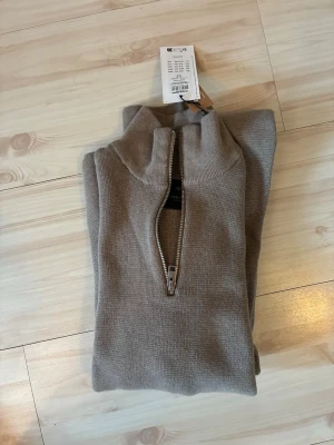 Beige stickad halvzip - Snygg beige stickad tröja från jack&jones med halvzip och hög krage. Tröjan har lång ärm och är tillverkad i mjukt material som passar perfekt till lager på lager. Enkel och stilren design utan mönster. Aldrig använd då lappen finns kvar men kan inte lämna tillbaka den. Nypris 600kr
