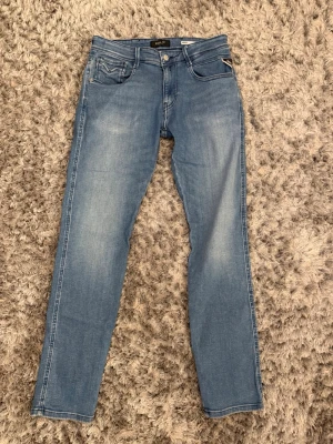 Ljusblå jeans från Replay - Säljer ett par ljusblå jeans från Replay med klassisk femficksmodell och raka ben. Jeansen har snygga slitningar framtill och detaljerade bakfickor med broderi. Tillverkade i mjuk denim som sitter skönt hela dagen.